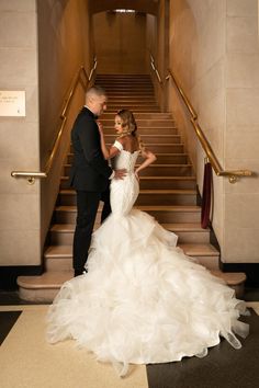 a bride and groom standing in front of the staircases at their wedding reception venue