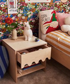 a small wooden table sitting next to a bed in a room with flowers on the wall