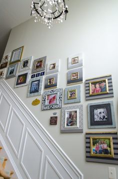 a staircase with pictures on the wall and a chandelier