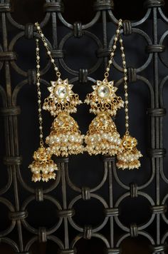 A traditional masterpiece, replete with traditional grandeur and an opulent design, these earrings are richly encrusted kundan jhumkas. The long hair chain with dangling trinkets of pearl suffuses the design with charm. Closure - Push-Back Style Tip - When it comes to getting a classic look, nothing can be better than pearls and kundan. This necklace set is fit for a woman who is fiercely independent yet rooted in traditional and cultural heritage, carving her own style with classic and timeless Jhumka Earrings Gold, Kundan Jhumkas, Traditional Jhumka, Kundan Jhumka Earrings, Fiercely Independent, Earrings Kundan, Unique Gold Jewelry Designs, Hair Chain, Sabyasachi Jewellery