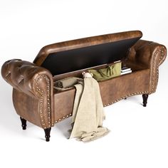 a brown leather bench with a blanket on it