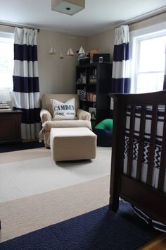 a baby's room with blue, white and black striped drapes on the windows