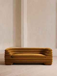 an orange couch sitting on top of a wooden floor next to a white wall in a room