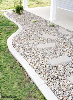 an outdoor walkway made out of rocks and gravel with a white house in the background