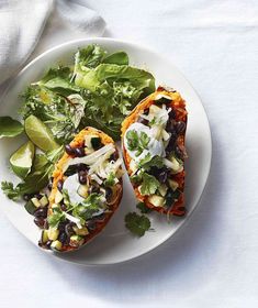 two stuffed sweet potatoes with black beans, avocado and cilantro on a white plate