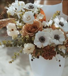 an arrangement of flowers in a white vase on a bride's wedding day,