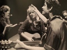 a group of people standing around each other with guitars in their hands and one person holding a guitar