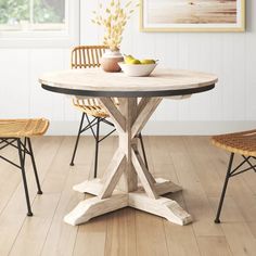 a dining table with two chairs and a bowl of fruit on it in front of a window