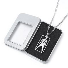 an open tin box with a necklace in it and a pendant on the inside that has a woman silhouette