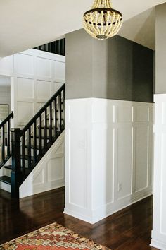 a chandelier hanging from the ceiling in a room with white walls and wood floors