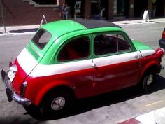 an old red, white and green car parked on the street