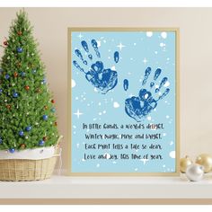 a christmas tree next to a blue and white card with handprints on it