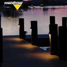 there is a dock that has some lights on it and the water in the background