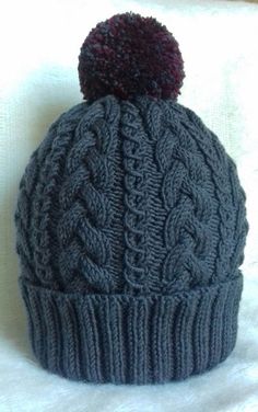 a gray knitted hat with a red pom - pom on the top