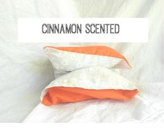 an orange and white pillow sitting on top of a bed with the words cinnamon scented above it