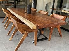 a wooden table sitting on top of a tiled floor next to a glass wall with windows