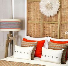 a bed with orange and white pillows on top of it next to a wooden headboard