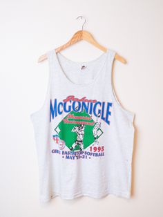 "Vintage graphic tank top with fantastic full front print. Four color graphic print celebrates the \"John McGonigle Memorial Girl's Fastpitch Softball Tournament of 1995\". Tank is excellent mid-weight cotton in ash heather gray.  Great for layering or worn on it's own. Tank brand is Fruit of the Loom. Size is XL, see measurements below for a good fit.  Some very slight discolorations spots towards belly, only noticeable if you are looking for them.  Great condition otherwise. Item is sold as is Retro Graphic Print Tank Top, Summer Throwback Tops With Graphic Print, Sleeveless Graphic T-shirt For Sports Events, Retro Crew Neck Tank Top With Graphic Print, Graphic Print Tank Top For Summer Sports Events, Retro Racerback Tank Top With Graphic Print, Summer Graphic Print Tank Top For Sports Events, Sports Tank T-shirt With Graphic Print, Graphic Print Sleeveless Tops For Sports Events