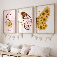 three framed pictures hang on the wall above a bench with pillows and sunflowers