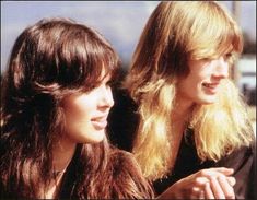 two women standing next to each other with long hair