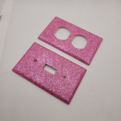 two pink glittered switchplate covers on a white surface