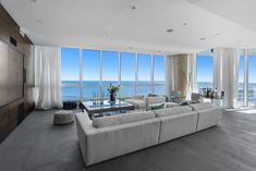 a living room filled with furniture and large windows overlooking the ocean on a sunny day