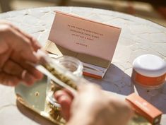 a person holding something in their hand while sitting at a table with other items on it