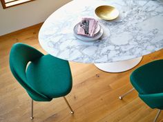 a marble table with three green chairs and a white round dining room table in the background