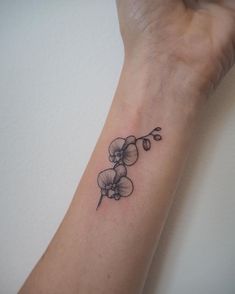 a woman's arm with a small flower tattoo on the left side of her wrist