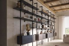 a living room filled with lots of furniture next to a wall mounted book shelf covered in books