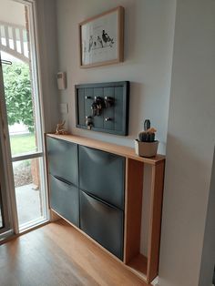 an empty room with a large window and wooden cabinet in the corner, next to a sliding glass door