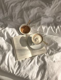 an open book and cup of coffee on a bed