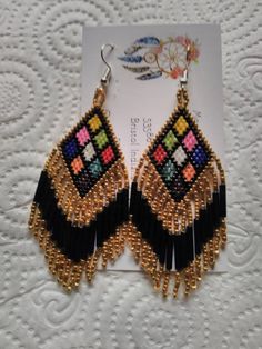 These Earrings are made by hand by me. There are 9 triangles in different colors bordered in Black and Gold. They have Gold and Iris Fringe approximately 1 1/4 inches long. They are in total 3 inches in length. They are made with Miyuki Delica size 11 seed beads. Made to Order means you purchase then I will make it within 3 days.I can make them bordered in other colors also.  Please take a close look at my work. Thank You So Very Much for your Interest Bohemian Triangle Earrings With Ear Wire, Handmade Triangle Bohemian Jewelry, Handmade Bohemian Triangle Jewelry, Multicolor Beaded Earrings With Latkans As Gift, Unique Handmade Triangle Earrings, Unique Triangle Earrings As A Gift, Bohemian Triangle Adjustable Earrings, Bohemian Adjustable Triangle Earrings, Handmade Triangle Earrings For Festival