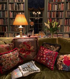 a couch with many pillows on it in front of a bookshelf full of books