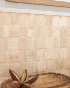 a wooden bowl sitting on top of a counter next to a tiled backsplash