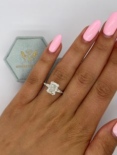 a woman's hand with pink manicured nails and a diamond ring