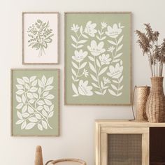 three framed floral prints on the wall above a chair and table with vases next to it