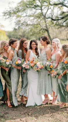 a group of women standing next to each other in front of a tree with flowers