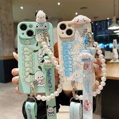 two cell phones with hello kitty charms attached to the back, and one has a keychain hanging from it