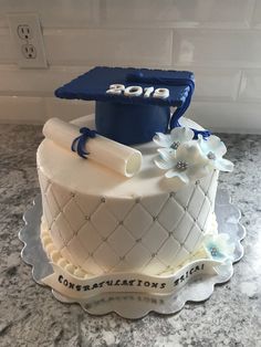 a graduation cake is decorated with blue and white flowers on a marble countertop in the kitchen