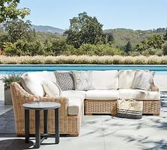 an outdoor patio with wicker furniture next to a swimming pool