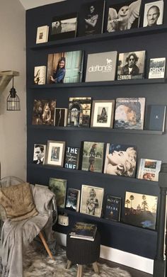 a living room filled with lots of books and pictures on the wall next to a chair