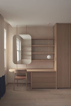 an empty room with a desk, mirror and shelves on the wall next to it