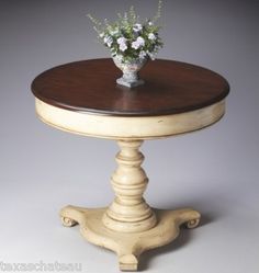 a small wooden table with flowers on it's top and bottom, against a gray background