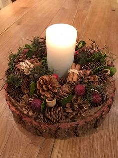 a candle sitting on top of a wooden table next to pine cones and other decorations