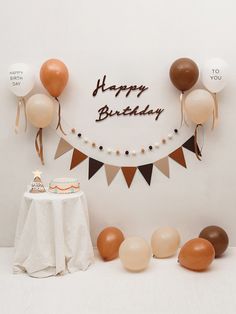 a birthday cake on a table with balloons and streamers in the shape of a happy birthday banner