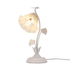 a white lamp that is on top of a table with a flower in the middle