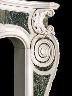 an ornate white fireplace with green marble on the top and bottom, against a black background