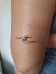 a woman's arm with a tattoo on it that has a wave coming out of the water