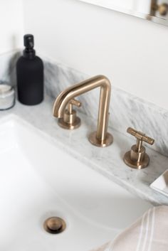 a bathroom sink with two faucets and soap dispenser